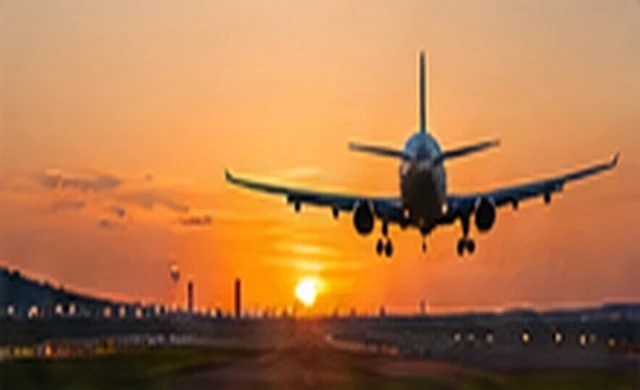 Airplane approaching runway at sunset